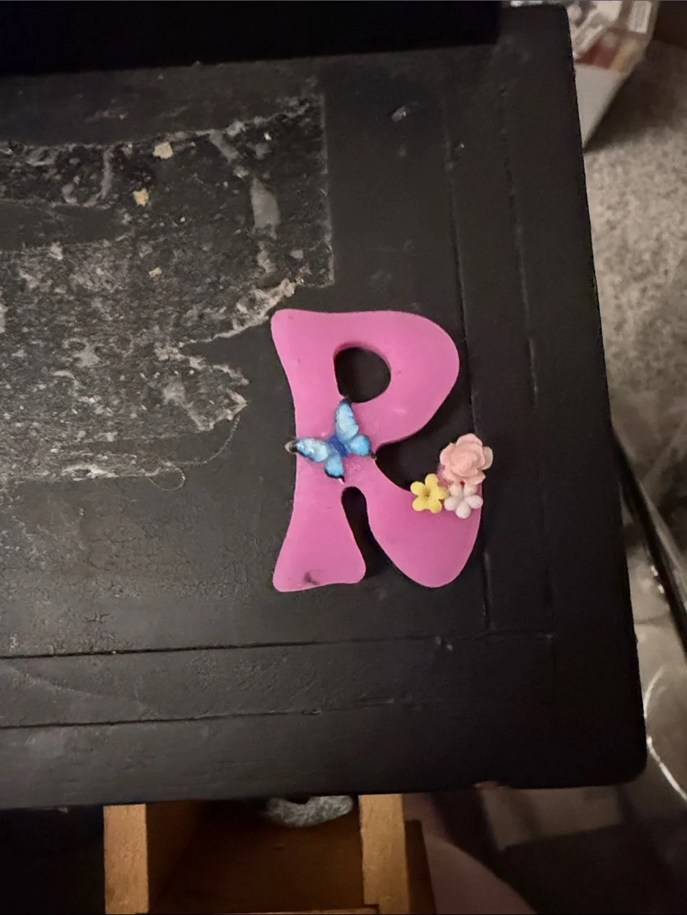 Letter R in pink with a blue butterfly and flowers